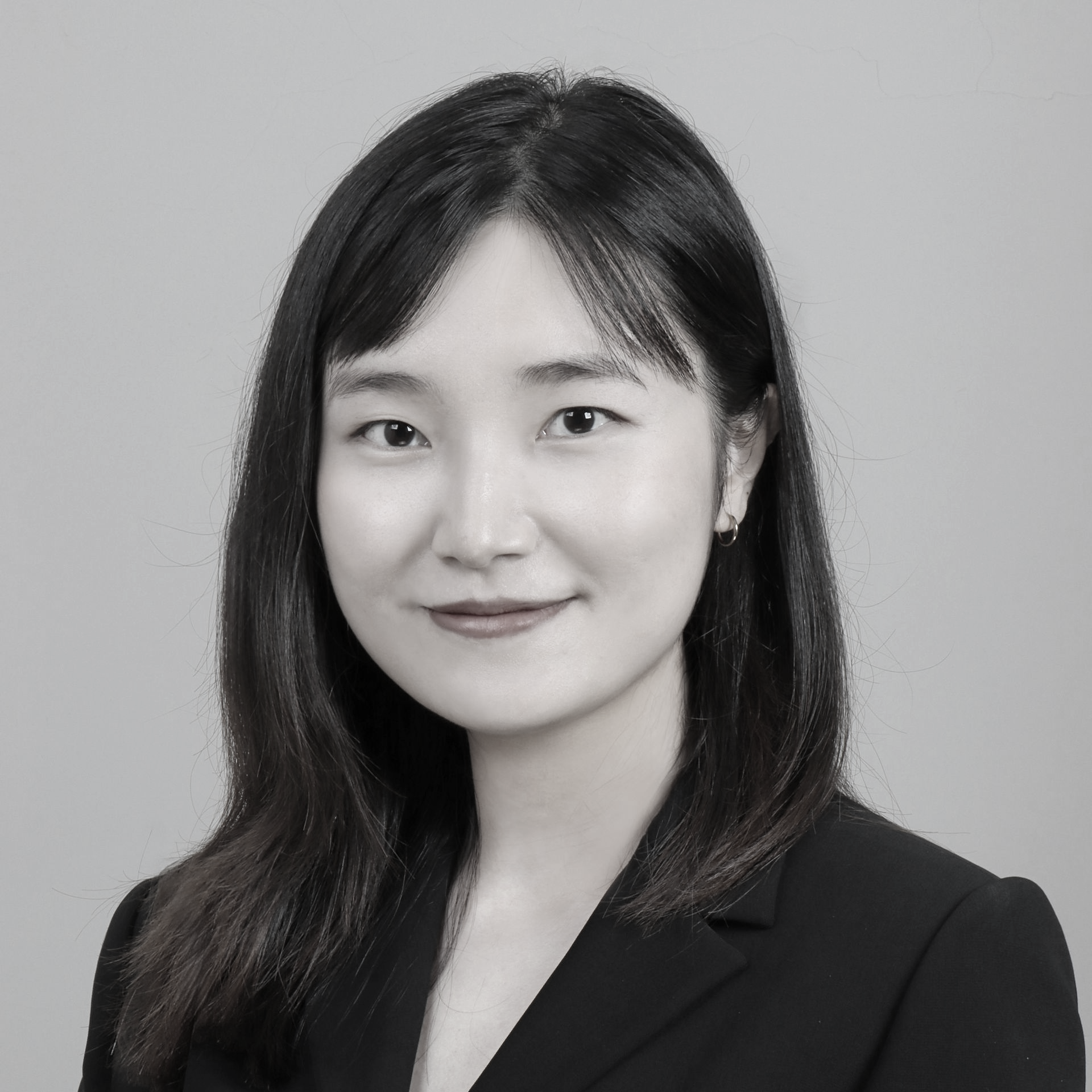 黑白照片中，一名身穿白色夾克的女子微笑著。