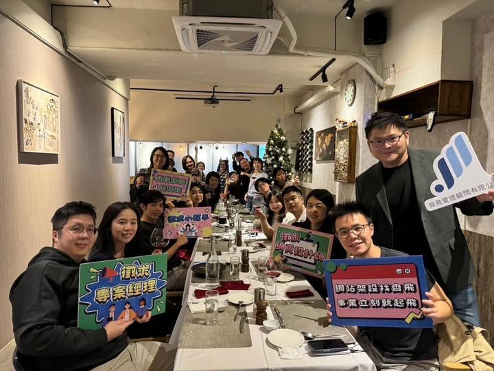 一群人坐在一張長桌旁,舉著牌子。