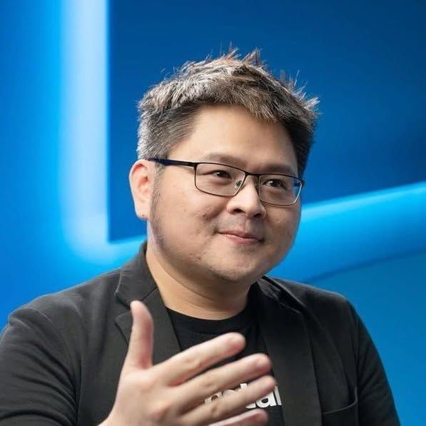一張穿著西裝和黑色襯衫的男人的黑白照片。