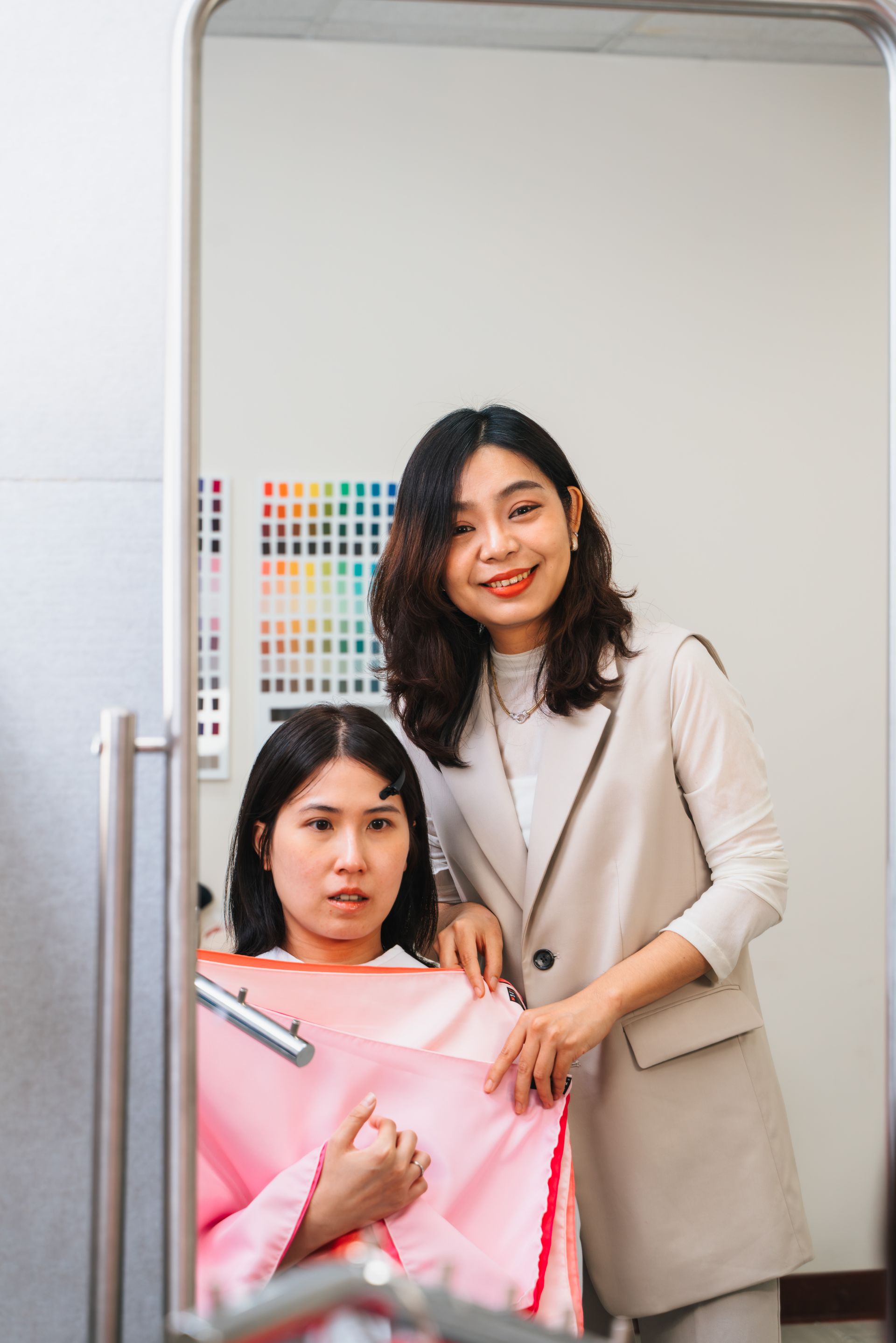 一個女人站在鏡子前,旁邊還有一個女人。