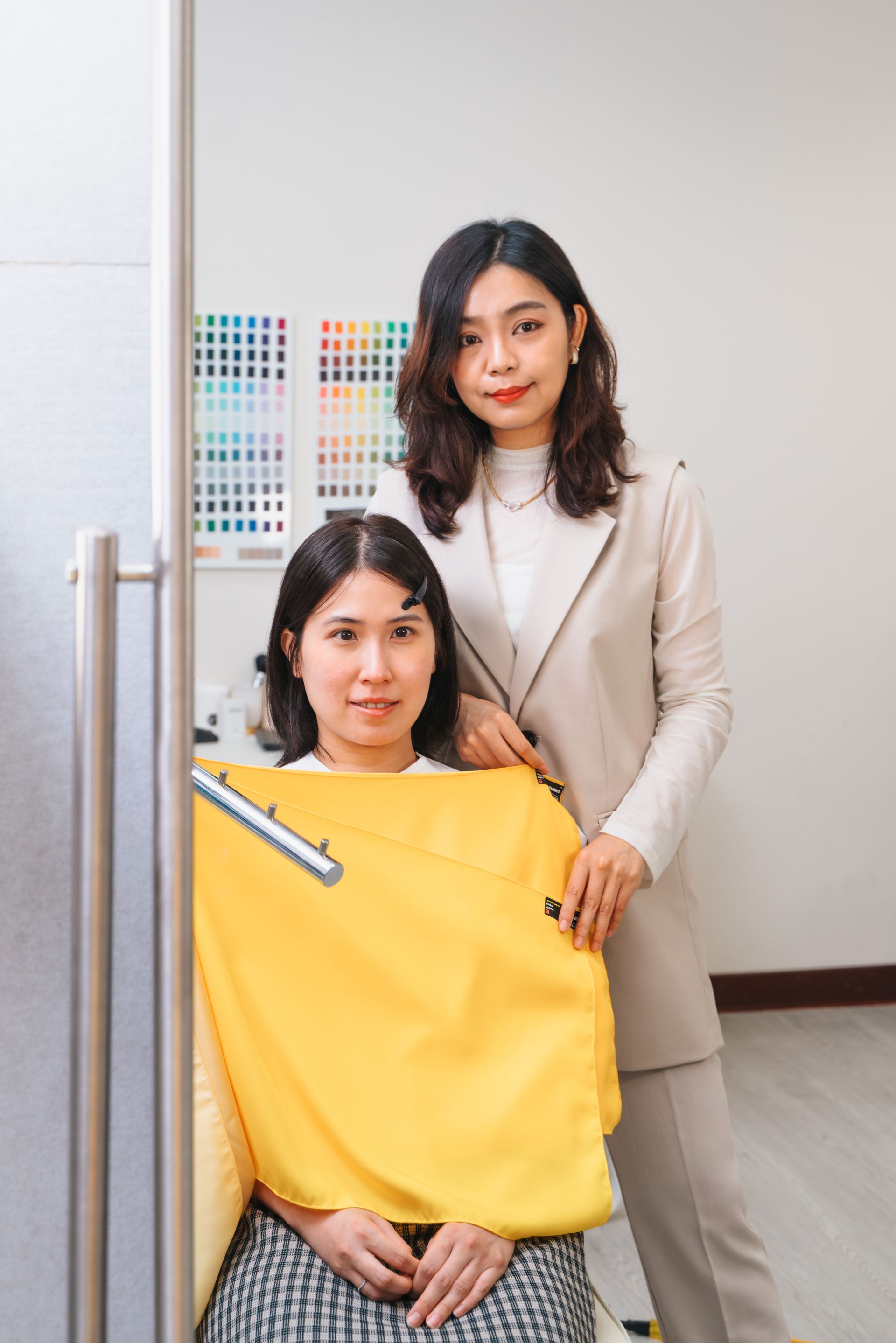 兩個女人並排站在一個房間裡。其中一名婦女身穿黃色斗篷。