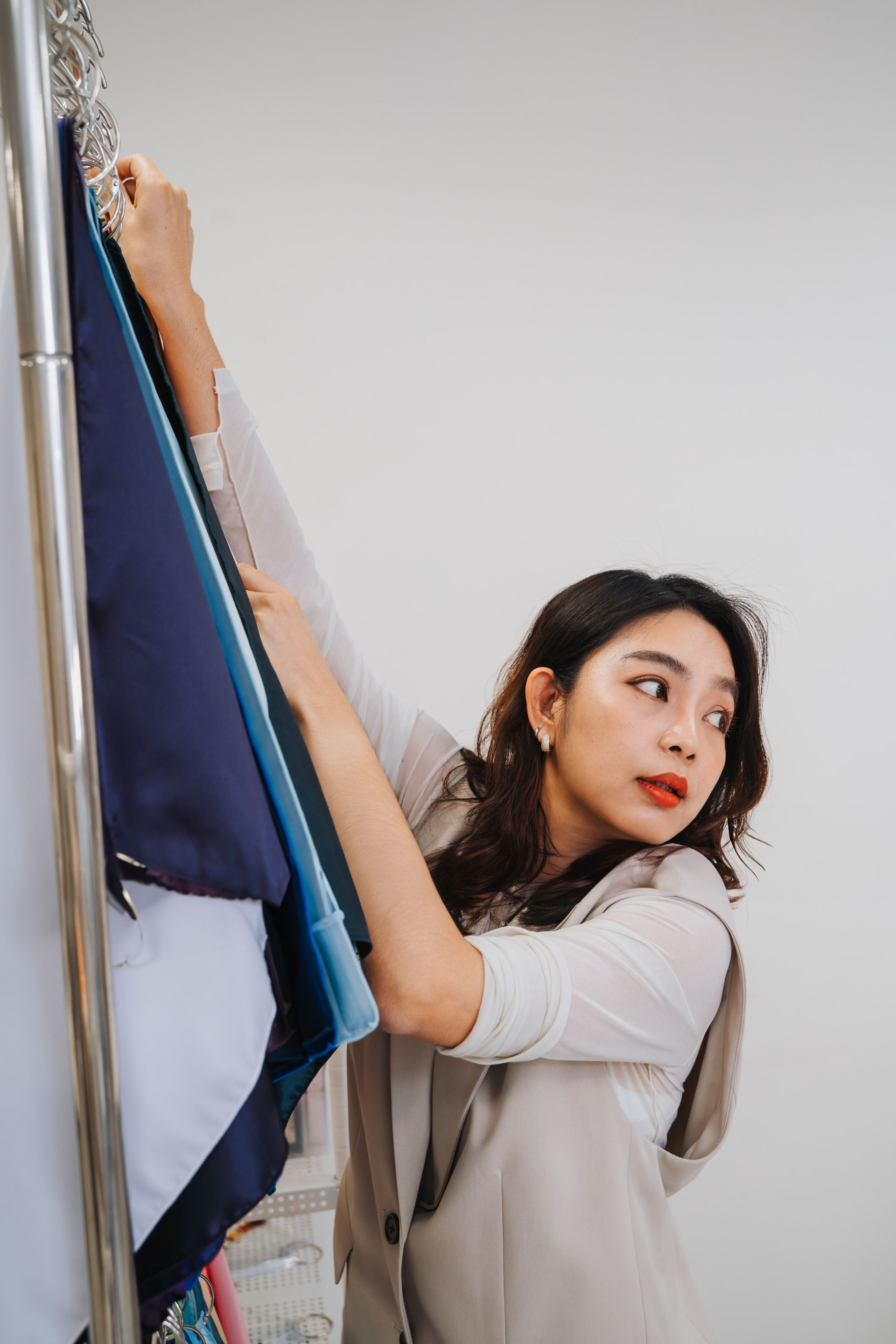 一個女人正在衣櫥裡的架子上掛衣服。