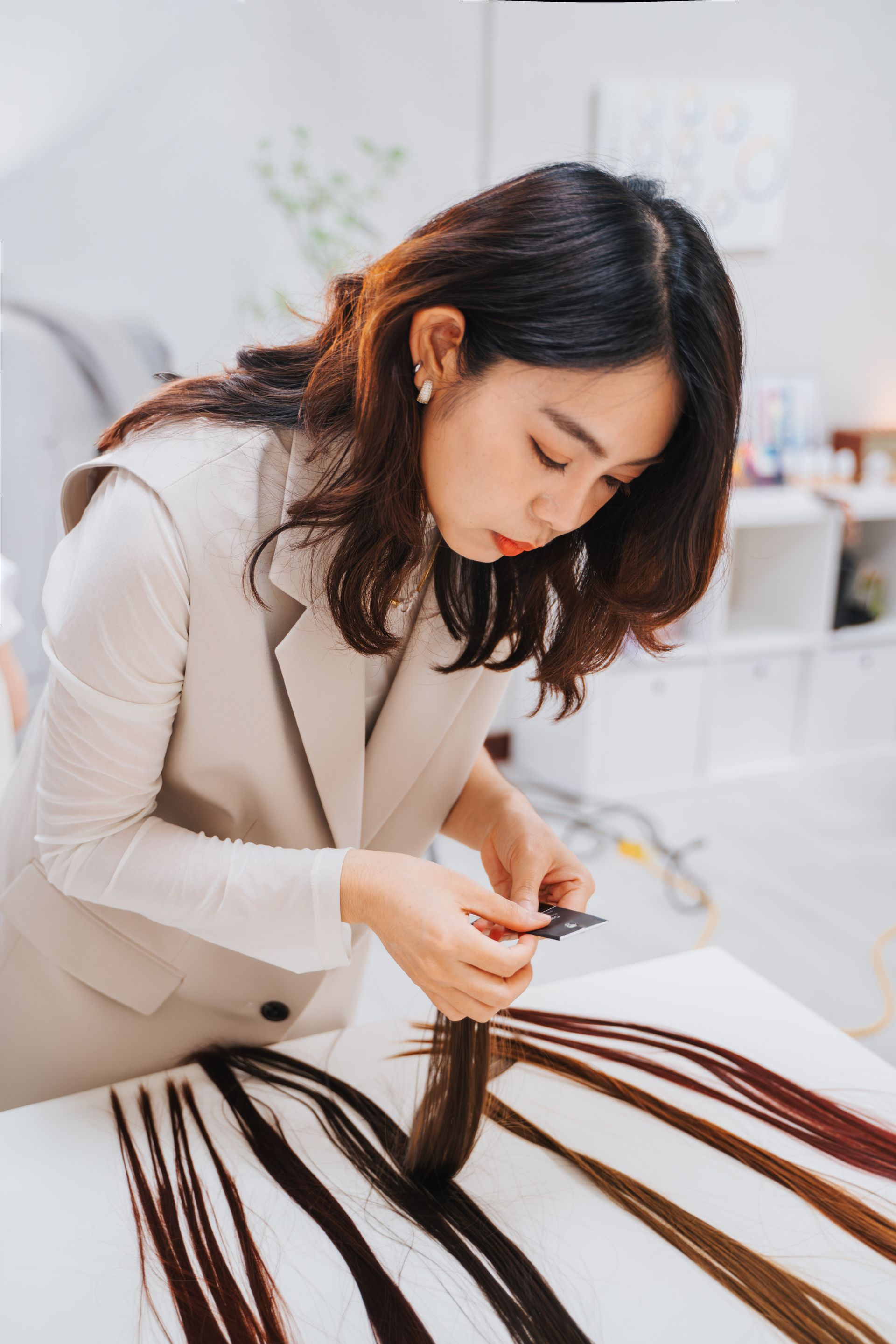 一個女人坐在一張桌子旁,手裡拿著一束接髮。