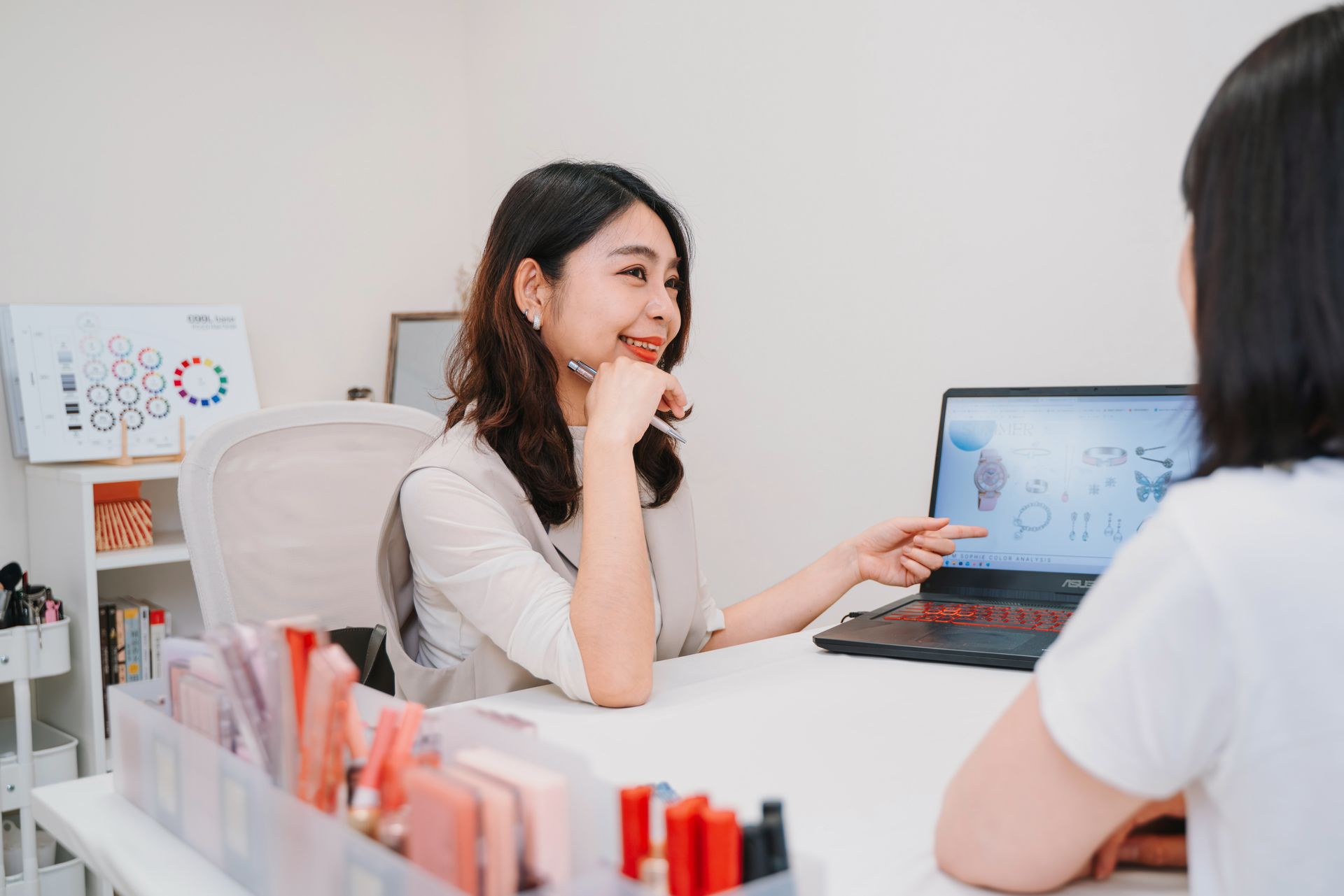 一位女士拿著筆記型電腦坐在桌旁,正在與另一位女士交談。
