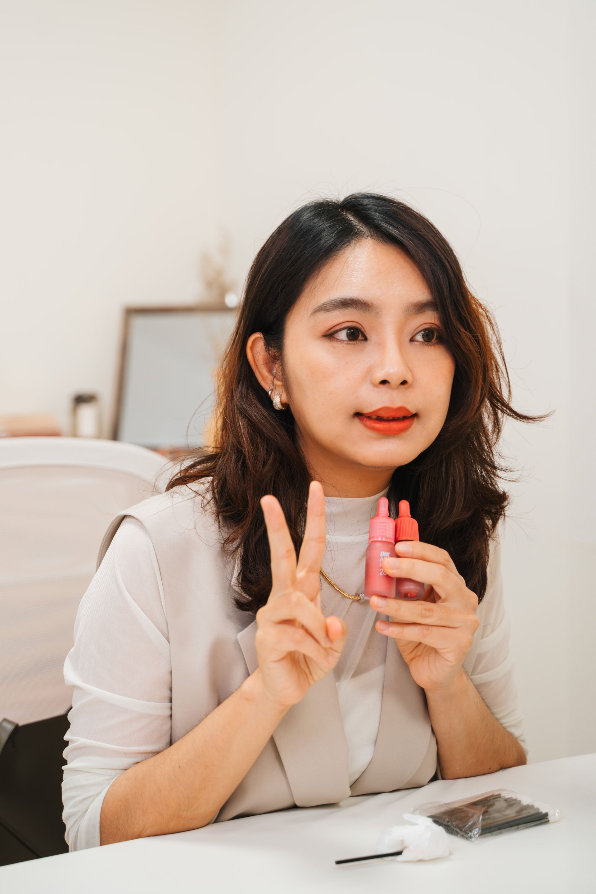 一個女人坐在桌邊,手裡拿著一瓶乳液。