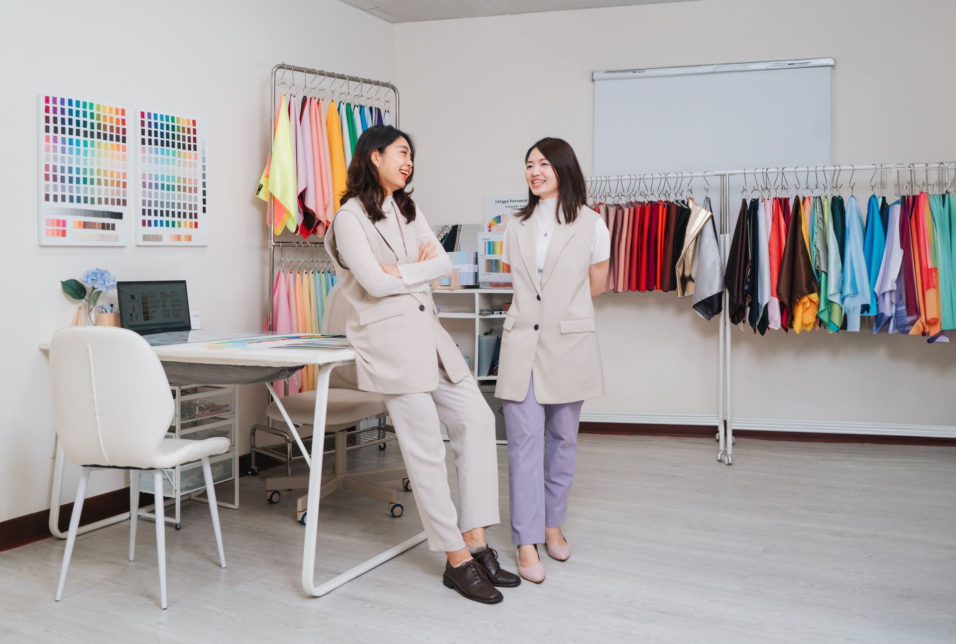 兩個女人並排站在一個房間裡,衣架上掛著衣服。
