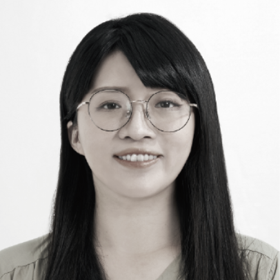 一張黑白照片中，一位穿著西裝和白襯衫的女人微笑著。