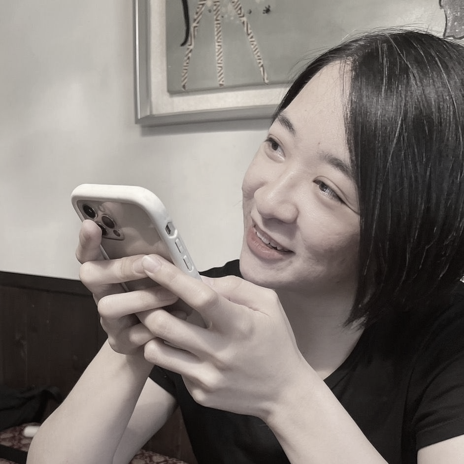 一張黑白照片中，一位穿著西裝和白襯衫的女人微笑著。