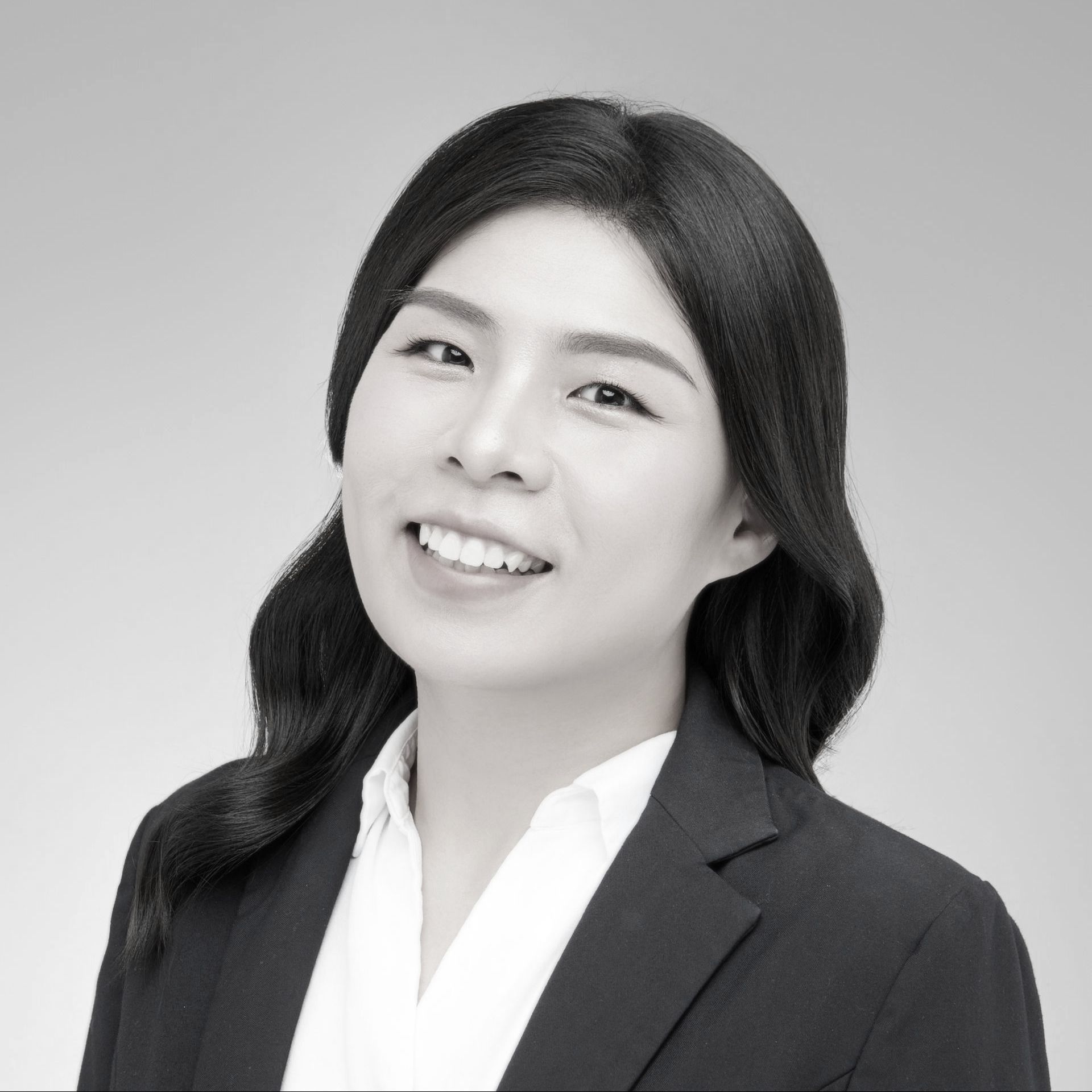 黑白照片中，一名身穿白色夾克的女子微笑著。