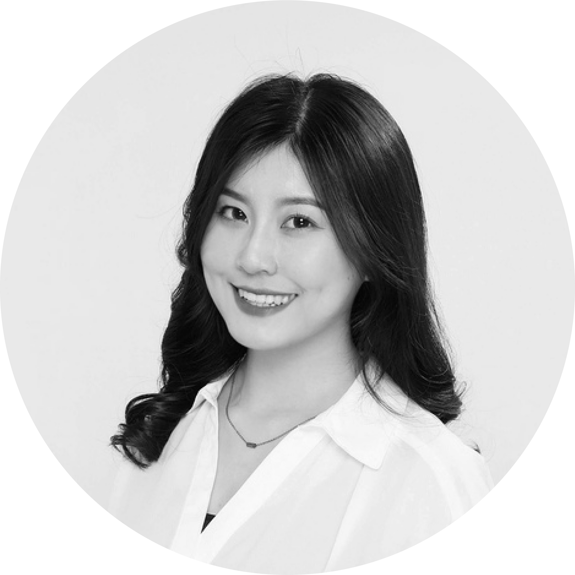 黑白照片中，一名身穿白襯衫的女子正在微笑。