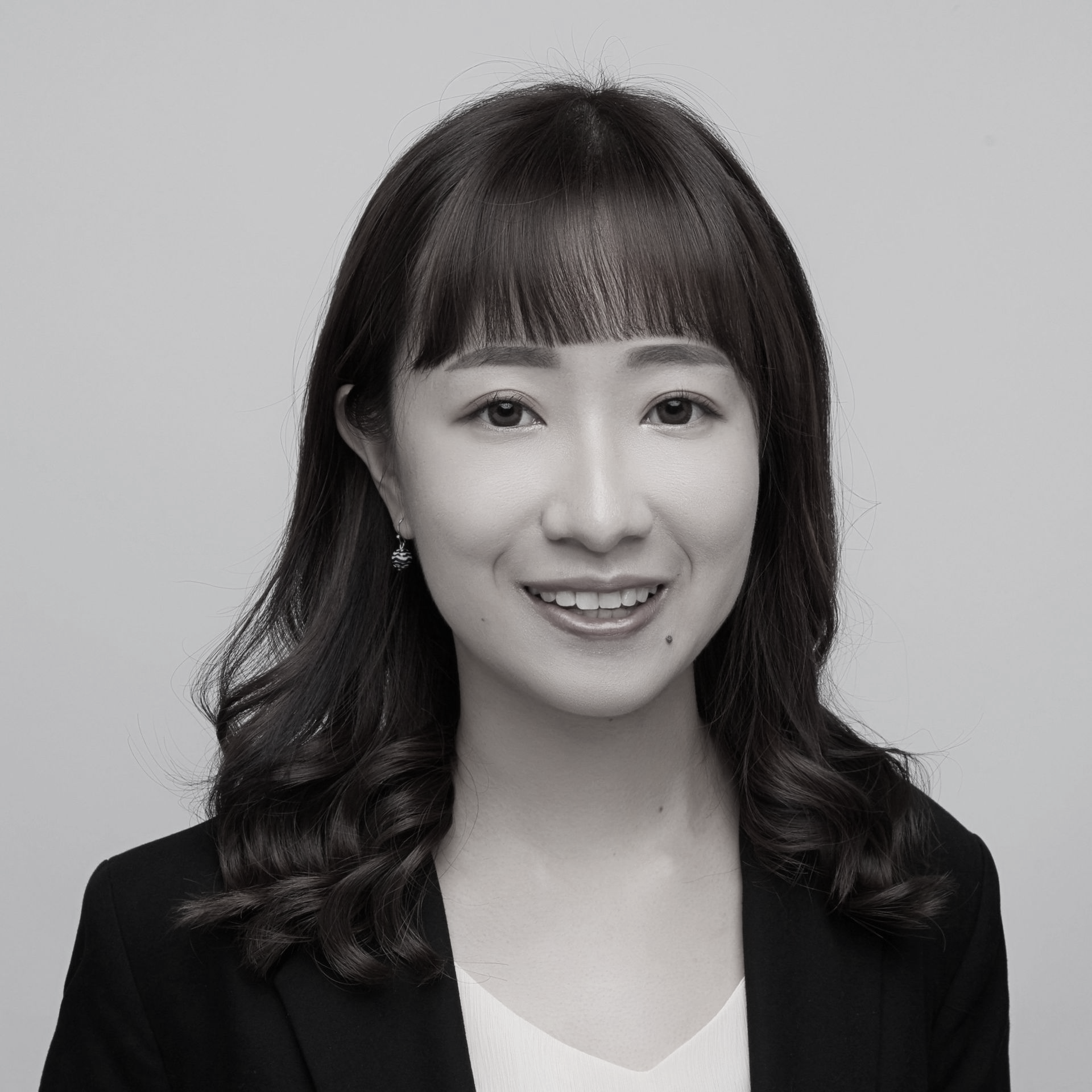 黑白照片中，一名身穿白色夾克的女子微笑著。