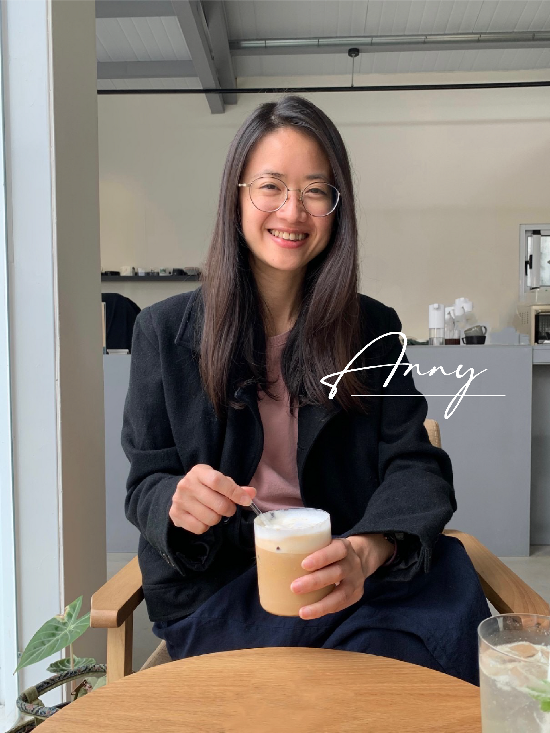 一個女人坐在桌邊,手裡拿著一杯咖啡。