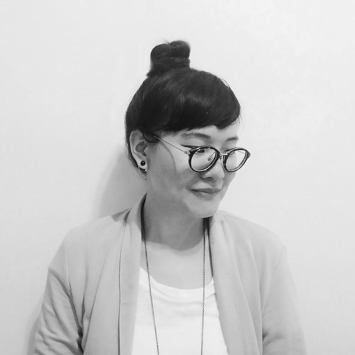 一張戴著眼鏡、綁著髮髻的女人的黑白照片。