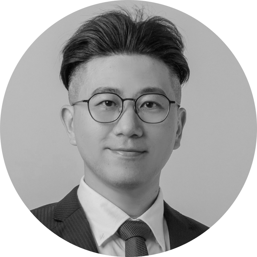 一張黑白照片，照片中是一個戴著眼鏡、穿著西裝、打著領帶的男人。