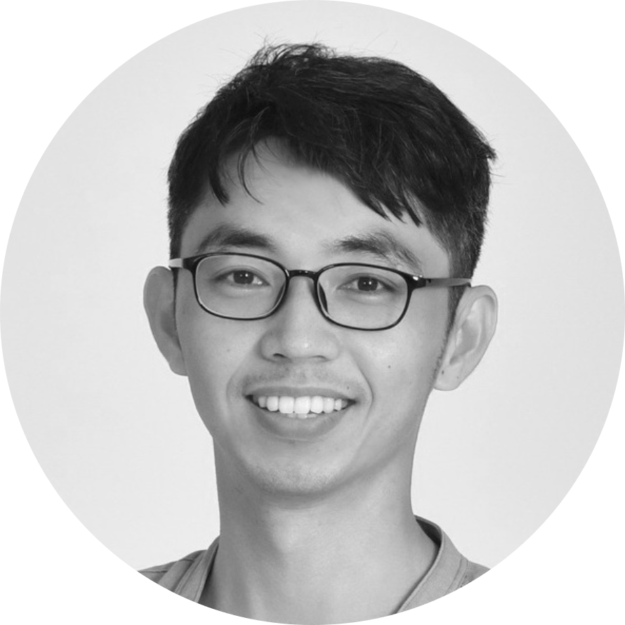 黑白照片中，一個戴眼鏡的男人微笑著。