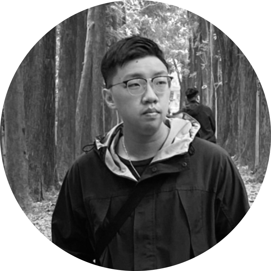 一個戴著眼鏡、穿著夾克的男人站在森林裡。