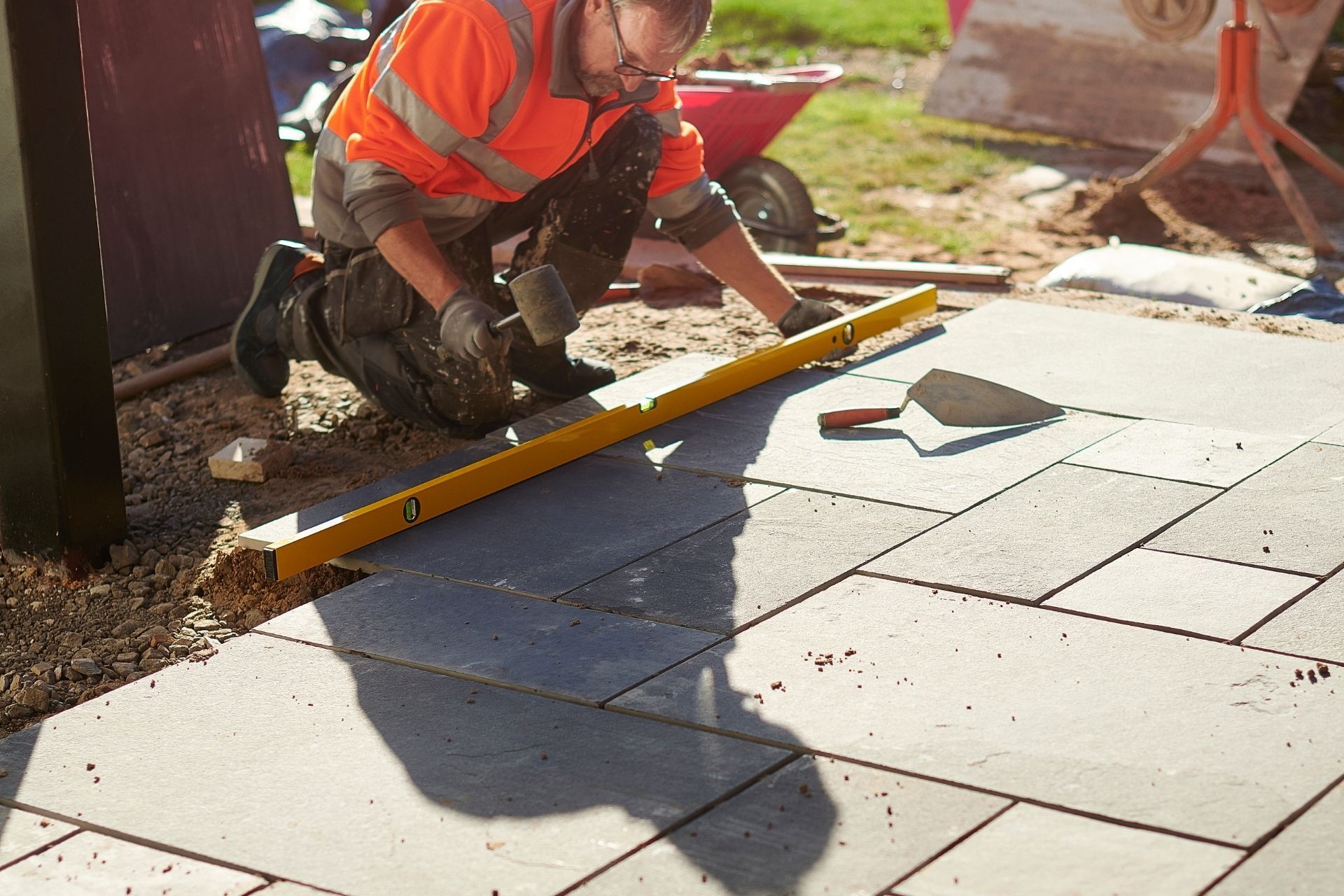 Worker leveling wet paving stones outdoors with a yellow spirit level
