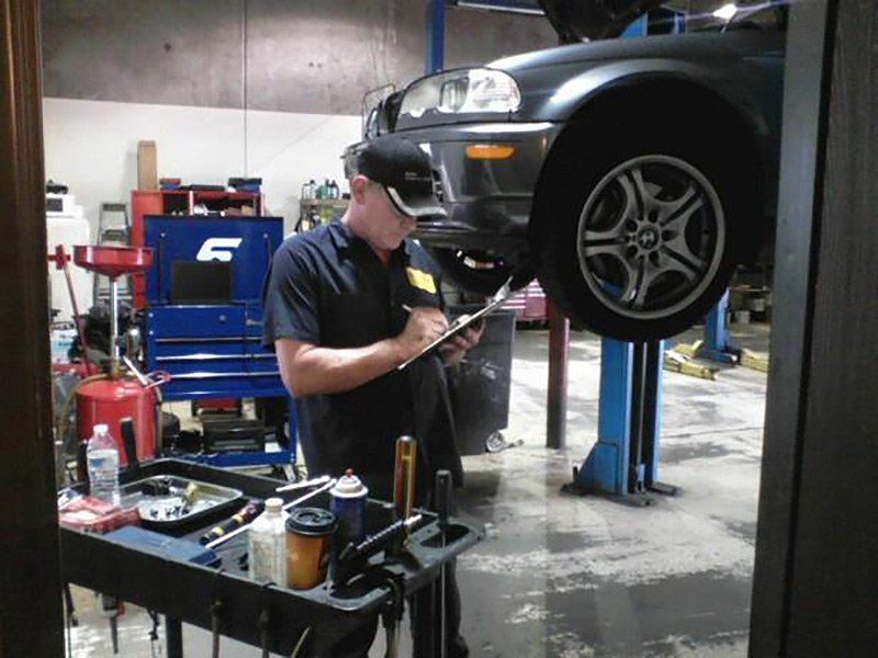Mechanic inspecting a car on a lift in an auto repair shop, with tools and equipment nearby