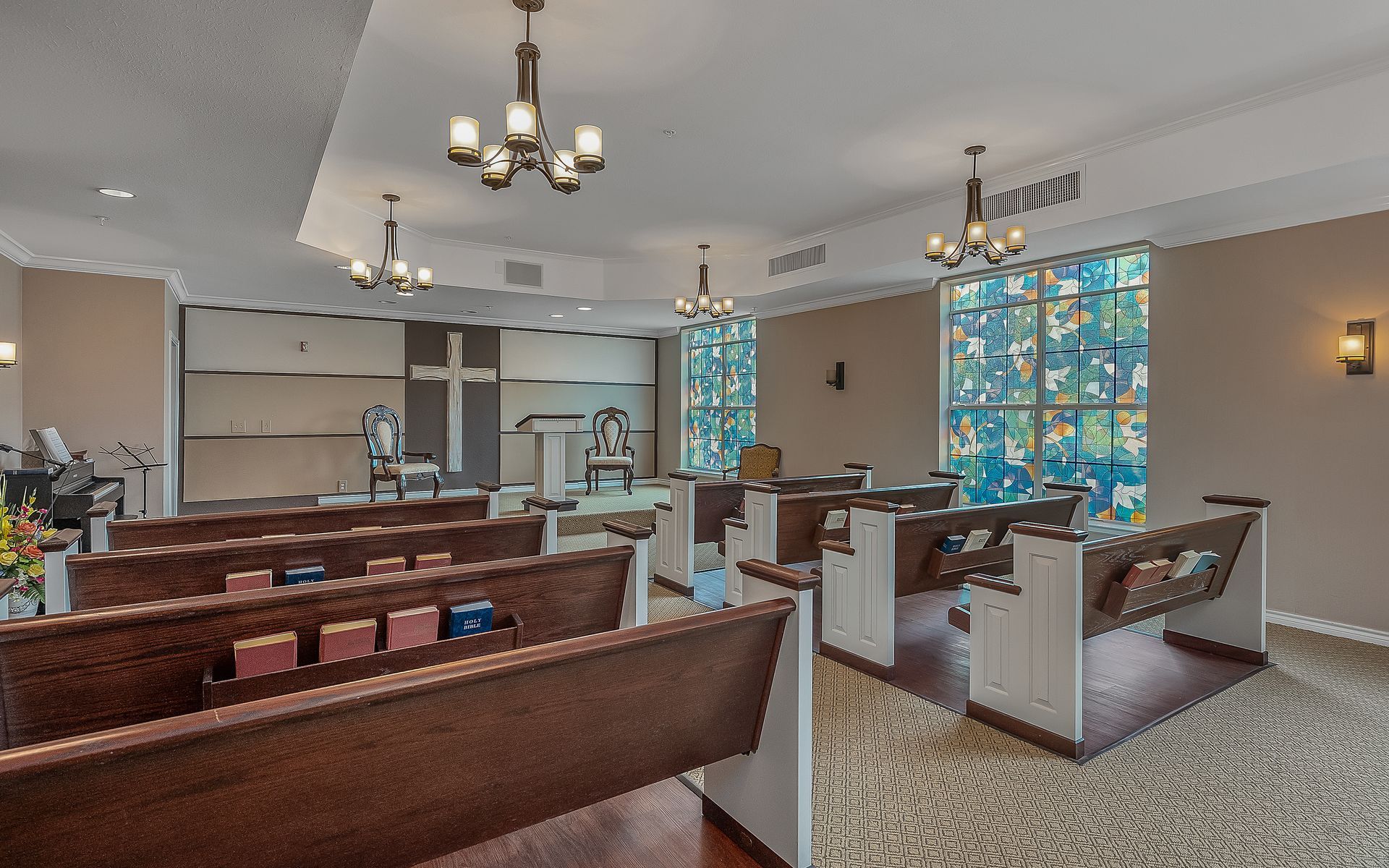 A church with a cross on the wall and stained glass windows.