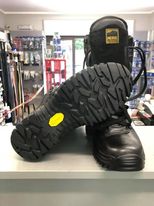 In un negozio di scarpe, uno stivale da lavoro nero è appoggiato su un bancone, con la suola rivolta in avanti.