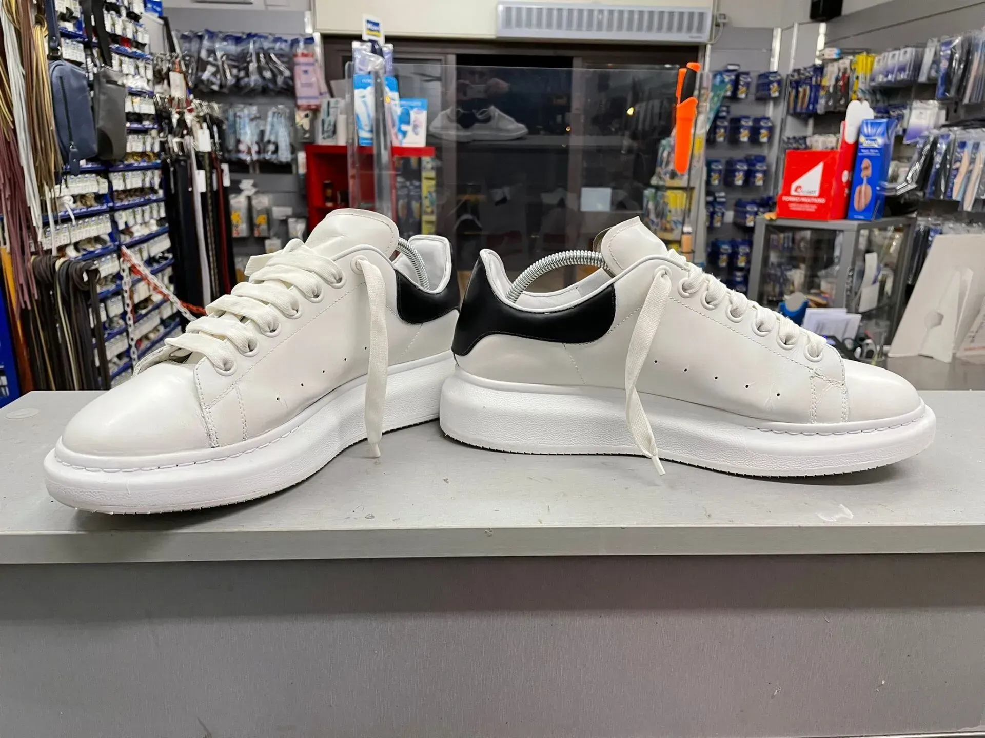 Scarpe da ginnastica bianche esposte una accanto all'altra sul bancone di un negozio di scarpe.
