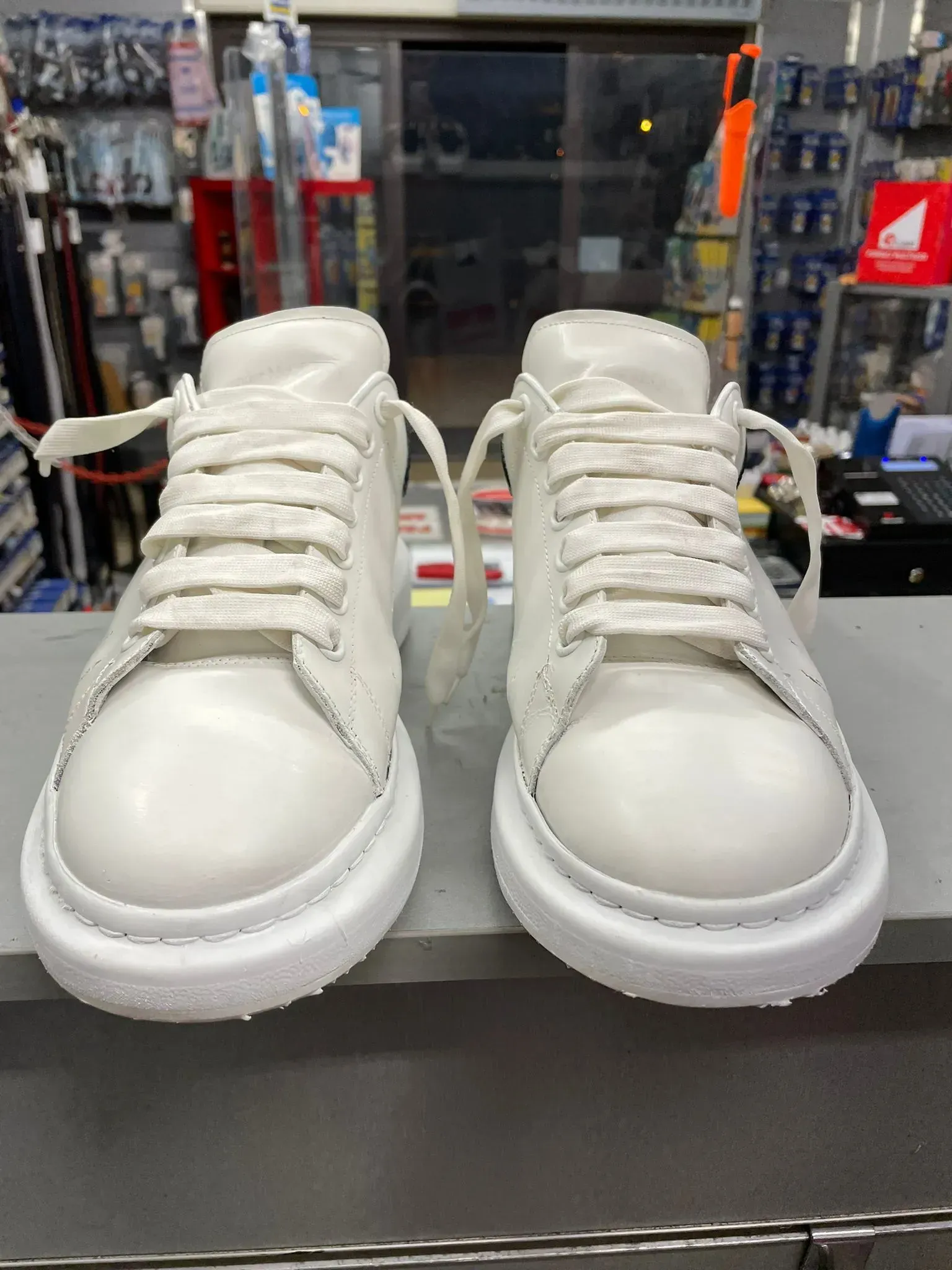 Un paio di scarpe da ginnastica alte bianche esposte sul bancone di un negozio, con uno sfondo sfocato che rappresenta un punto vendita.