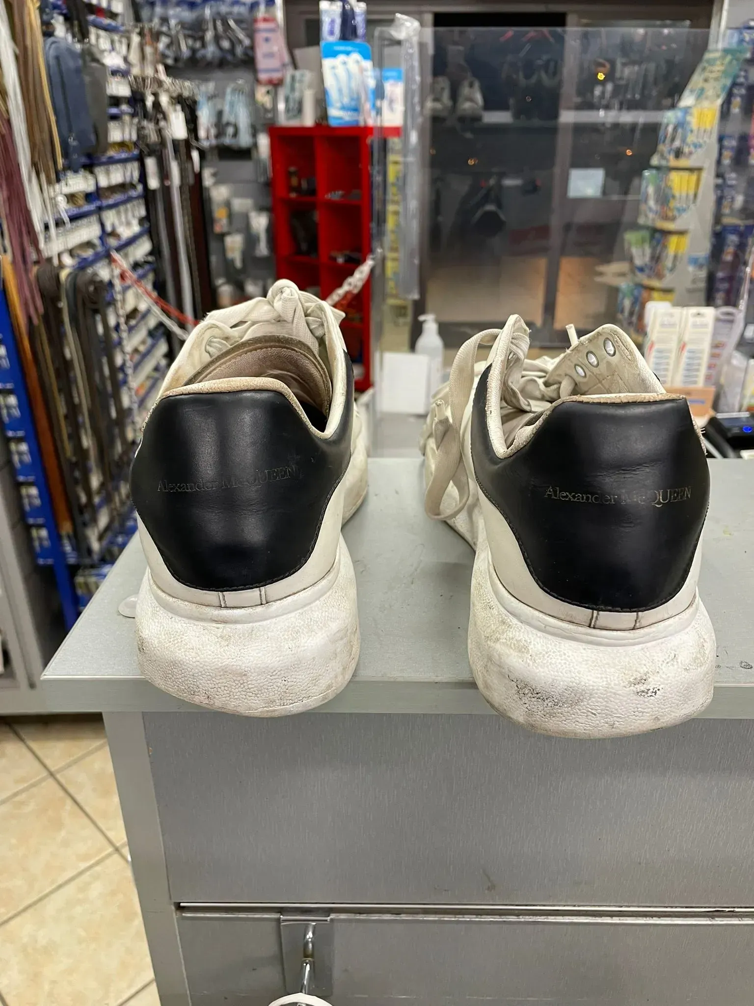 Un paio di scarpe da ginnastica nere con suola bianca esposte sul bancone di un negozio.