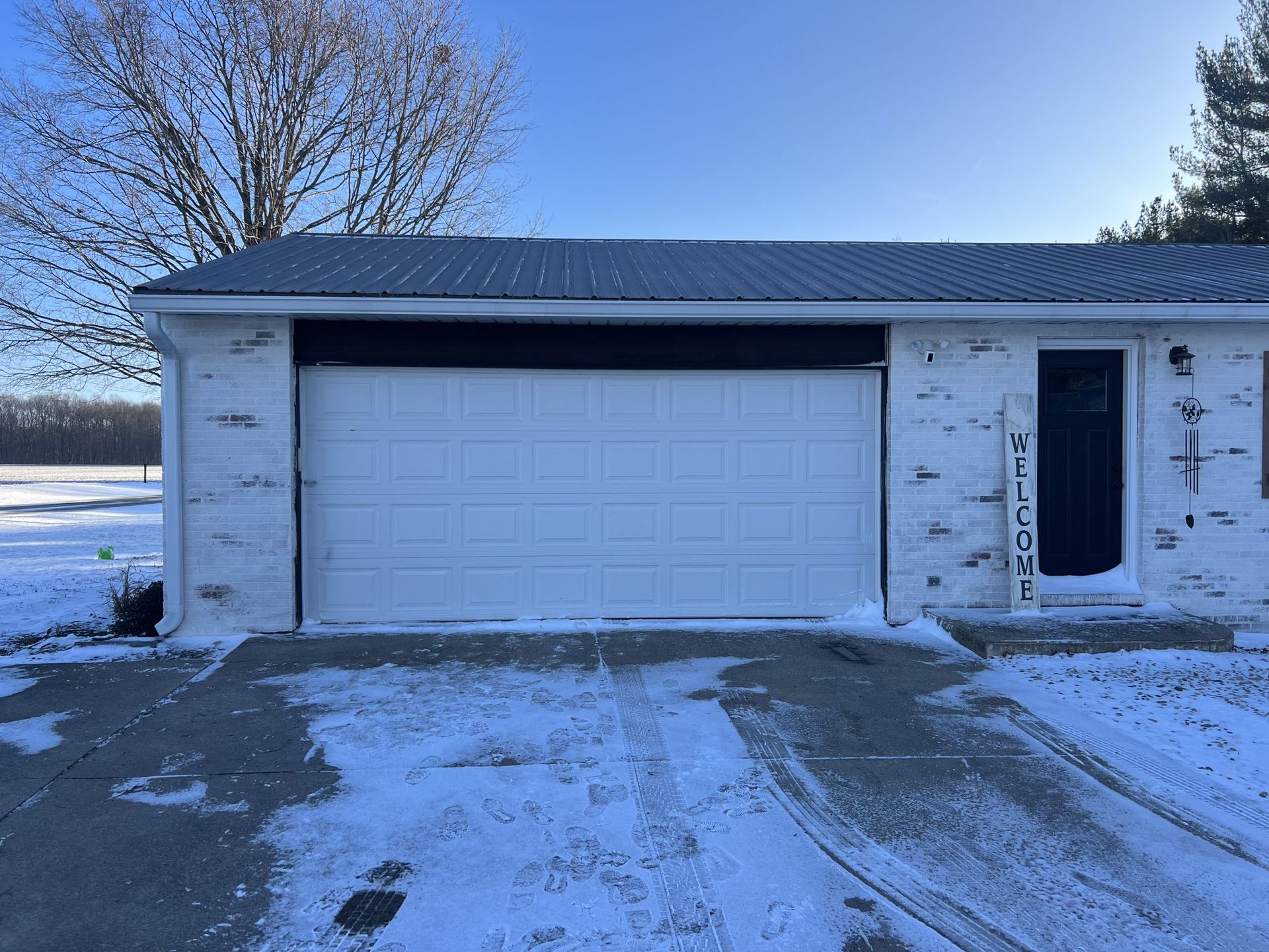 Snowy suburban house with a white garage door and driveway in winter.