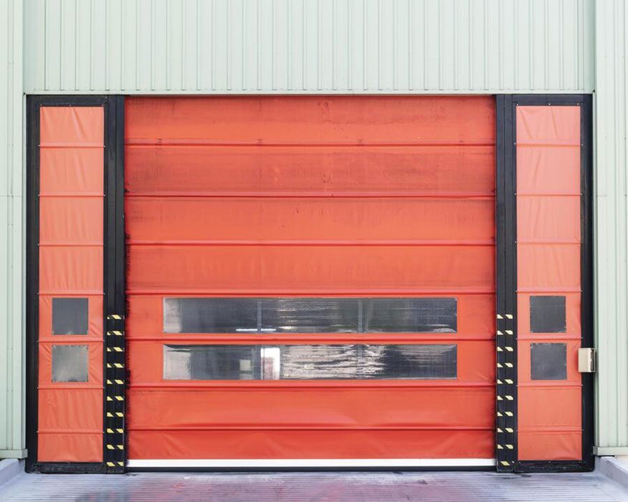 Orange industrial roll-up door with narrow windows in a warehouse loading bay
