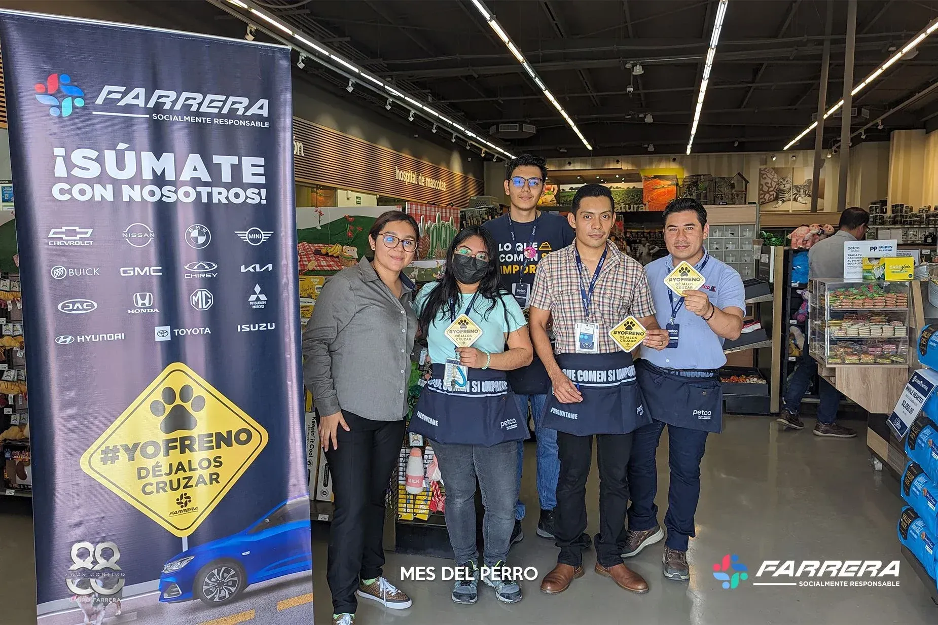Cinco personas de pie en un almacén junto a una pancarta con el lema “Símate con nosotros” y una exhibición de productos.