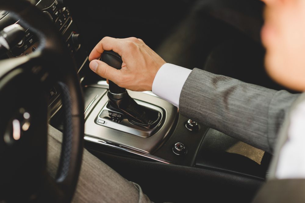 Conductor cambiando de marcha en un coche, mano en la palanca de cambios y volante visible