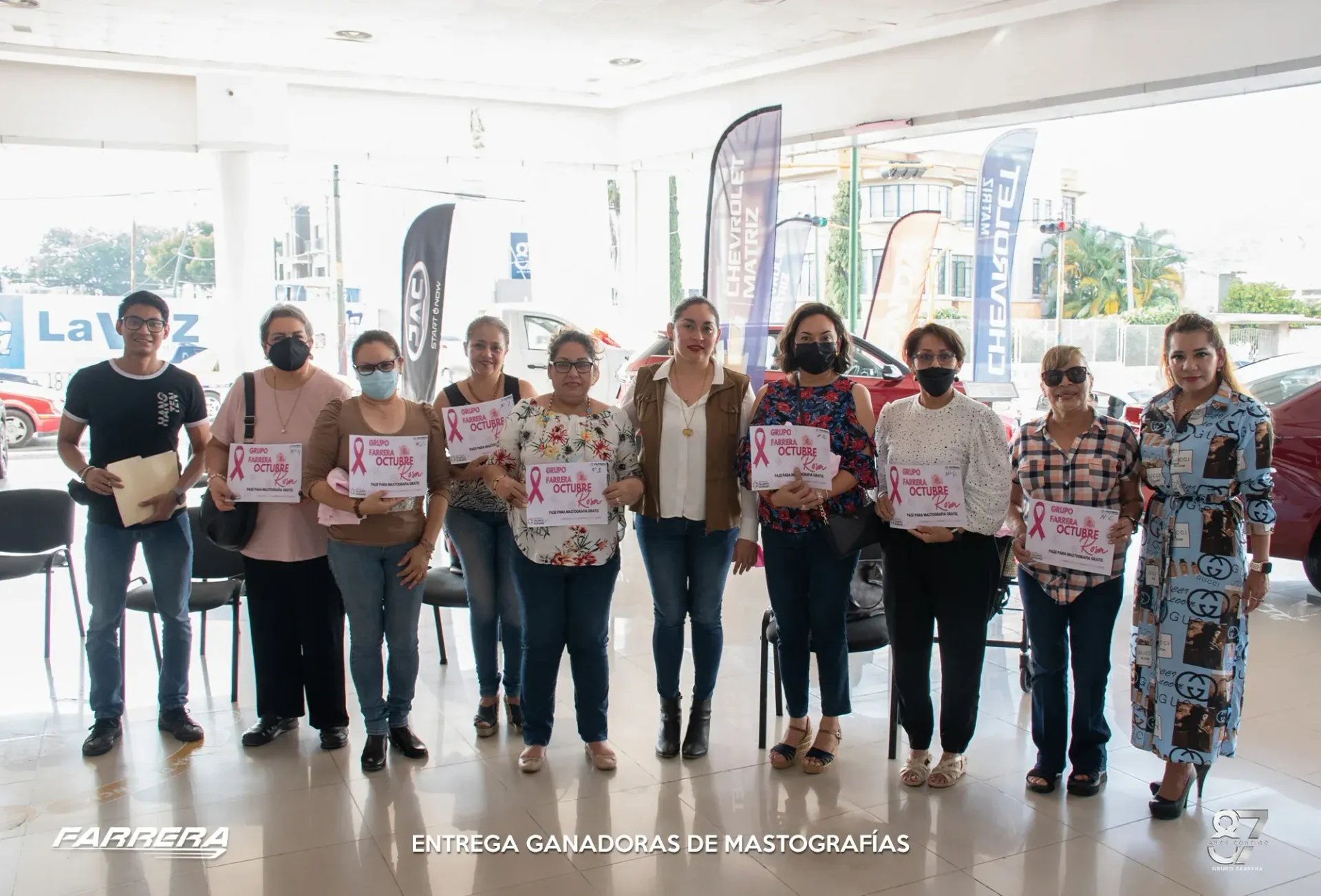 Grupo de personas con carteles, de pie juntas en un vestíbulo interior muy luminoso durante un evento.