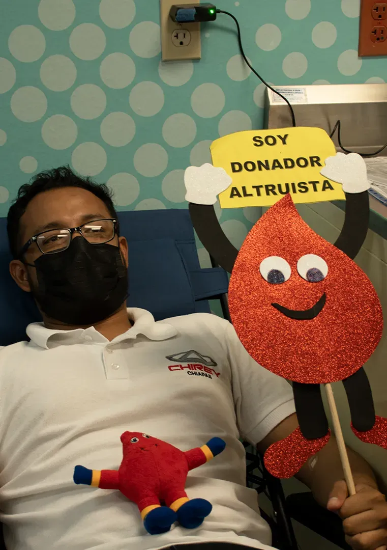 Hombre recostado junto a un cartel rojo sonriente que dice