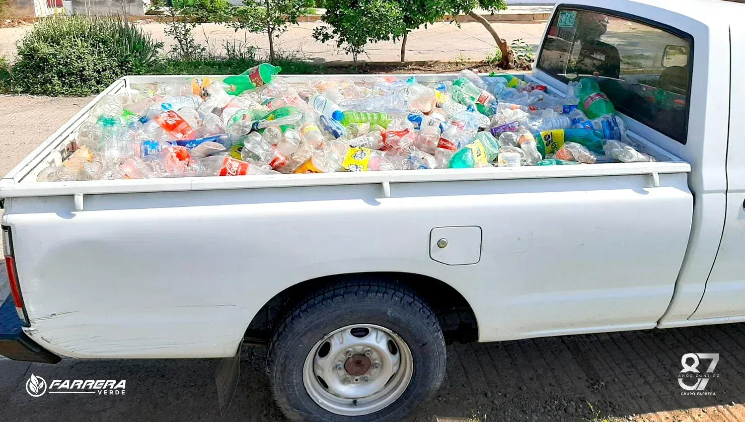 La caja de una camioneta blanca rebosante de coloridas botellas y recipientes de plástico al aire libre.