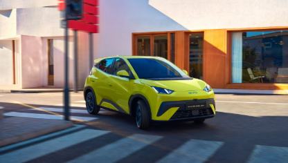 Un SUV amarillo brillante circula por una calle de la ciudad pasando junto a edificios modernos.