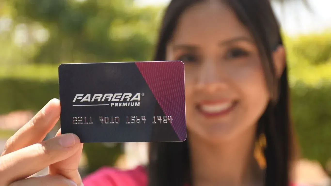 Mujer sosteniendo una tarjeta de crédito Farrara negra al aire libre, sonriendo al fondo.