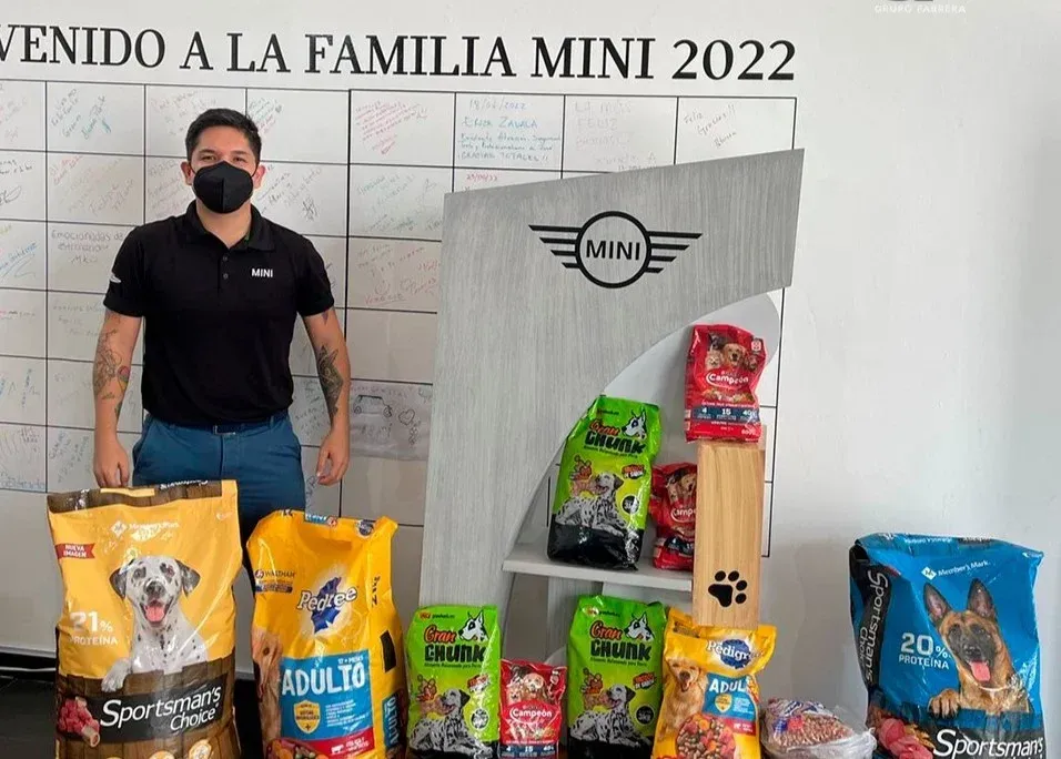 Hombre de pie junto a bolsas de comida para mascotas apiladas