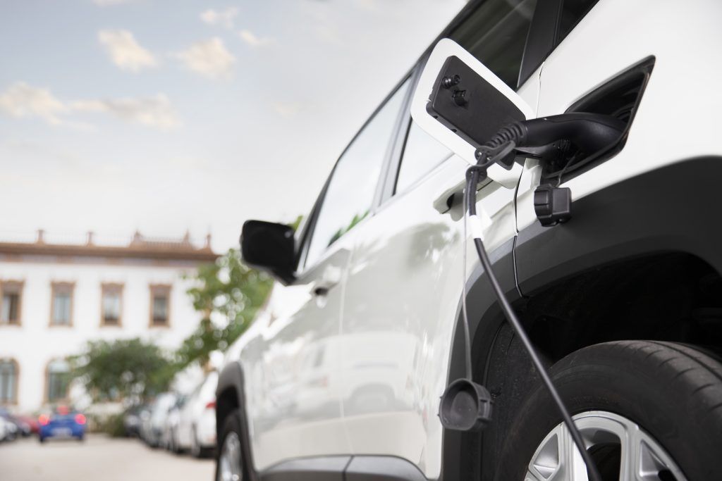 Carga de un coche eléctrico en una estación al aire libre frente a un edificio.
