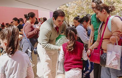 Una multitud se congregó al aire libre mientras un hombre hablaba con un niño que vestía un suéter rojo