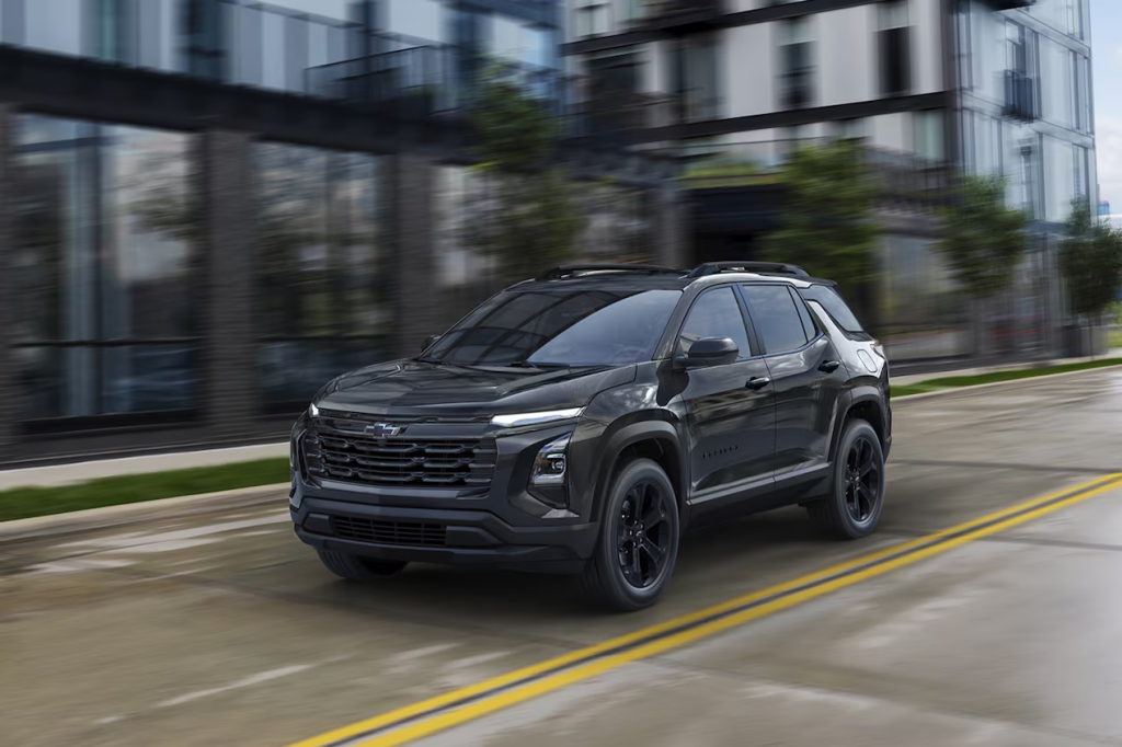 Un SUV negro circula por una calle mojada de la ciudad, junto a edificios modernos.