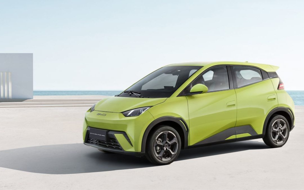 SUV compacto de color verde lima estacionado en una soleada carretera junto a la playa con el océano de fondo.