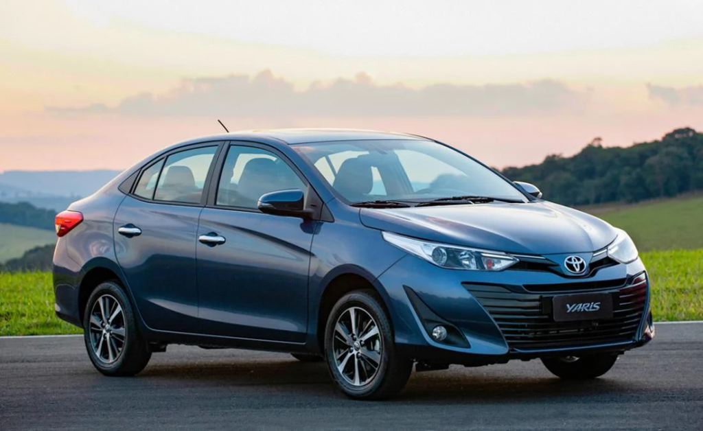 Sedán azul estacionado en una carretera al atardecer con colinas al fondo.