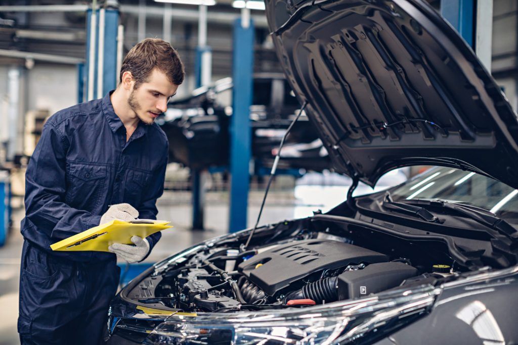 Mecánico inspeccionando el motor de un automóvil en un taller de reparación de automóviles