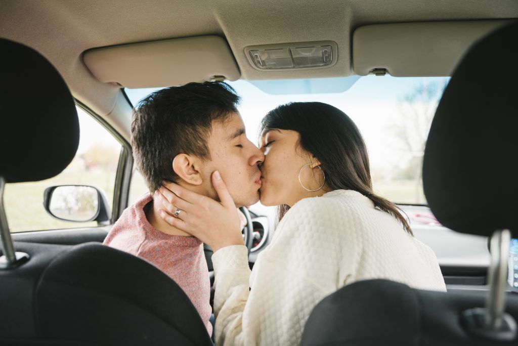 Dos personas besándose en el asiento trasero de un coche, una de ellas sujetando la cara de la otra.