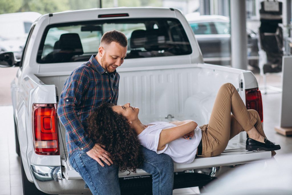Dos personas en la parte trasera de una camioneta, una acostada mientras la otra las revisa.