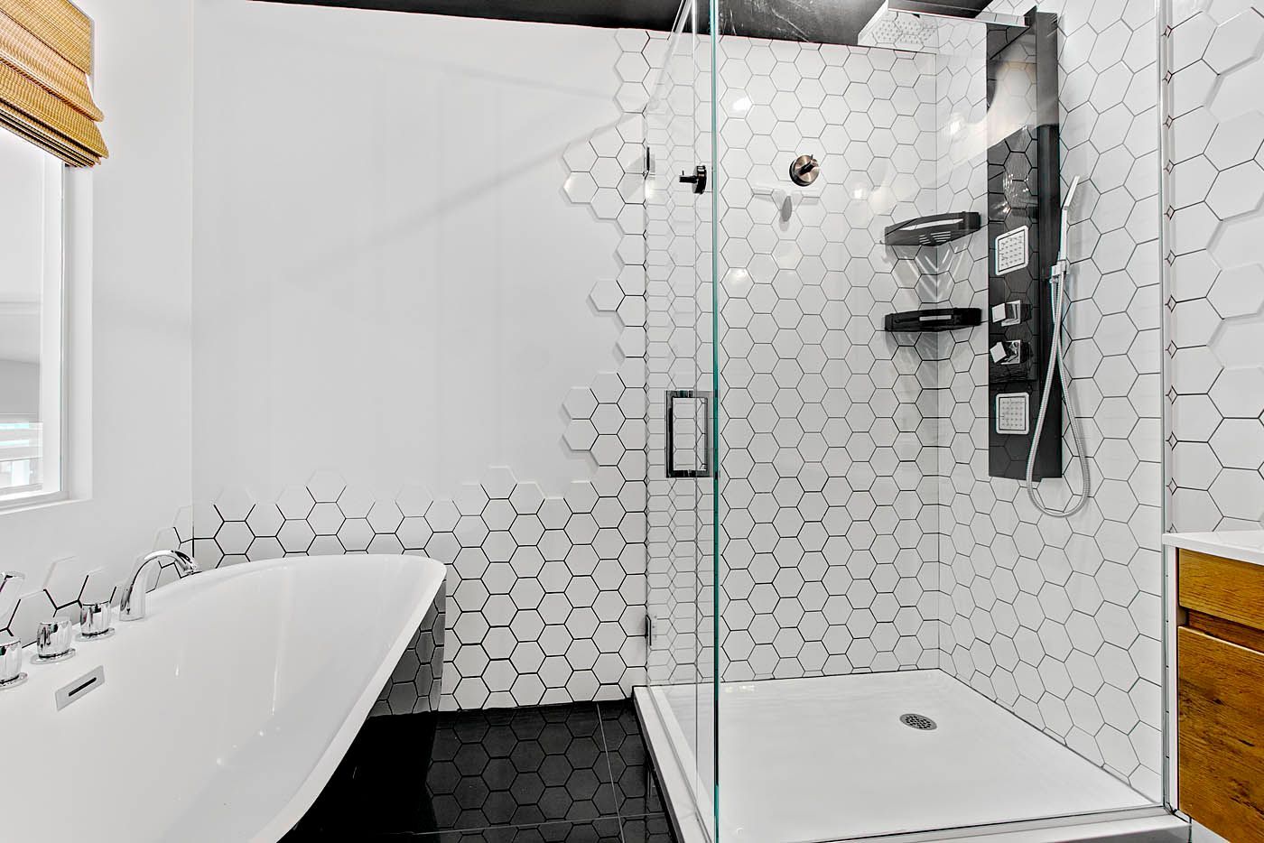 Salle de bains moderne blanche avec baignoire îlot, douche vitrée et carrelage noir au sol