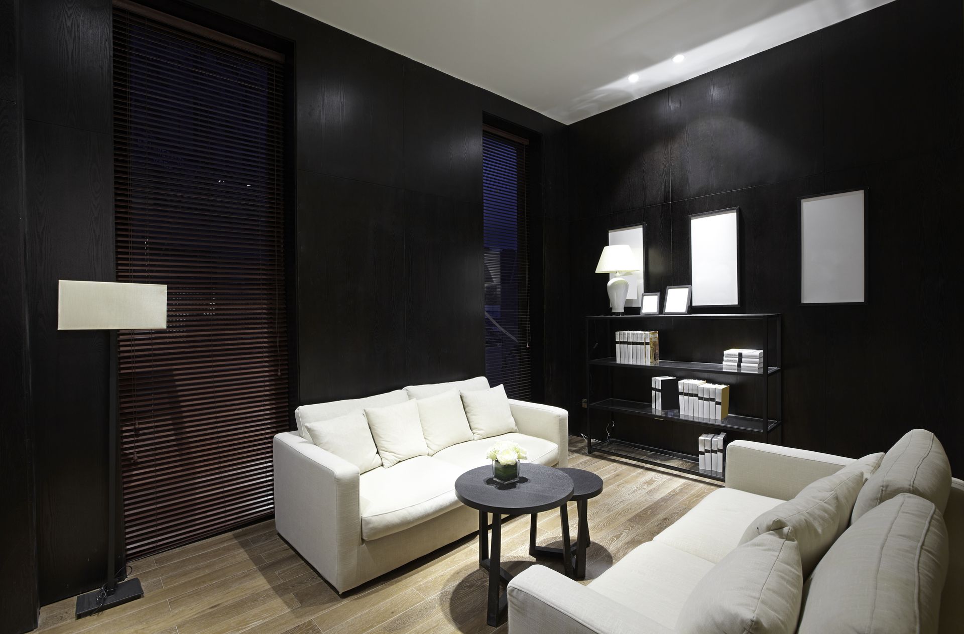 Living room with black walls, white couches, round table, and floor lamp.