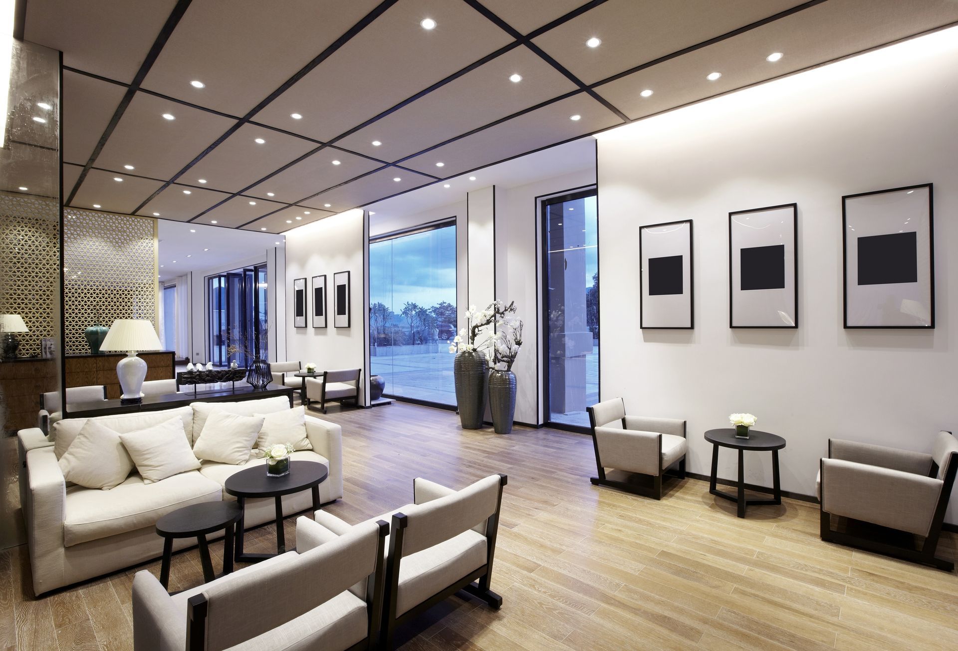 Elegant, modern lounge area with seating, artwork, large windows, and recessed lighting.