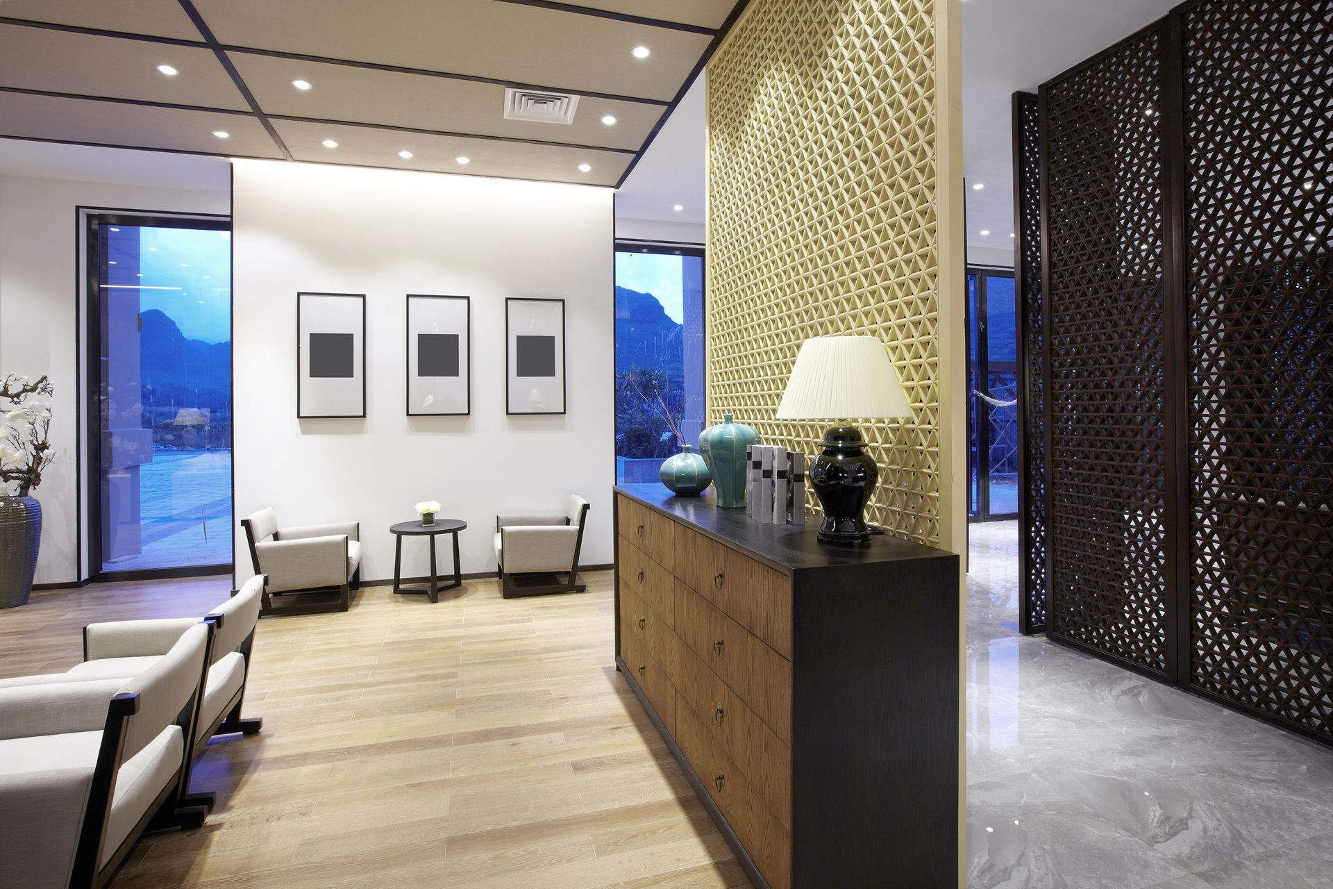 Modern interior with wooden floors, neutral walls, decorative screens, and minimal furniture.