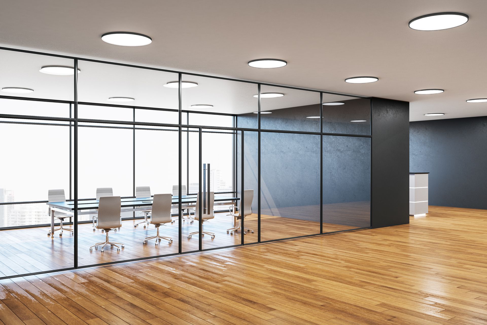 A glass-walled conference room with chairs and a table sits on a wooden floor in a modern, open-plan office.